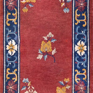Red runner rug with a scattered floral pattern and a wide dark blue, yellow, and red decorative border.