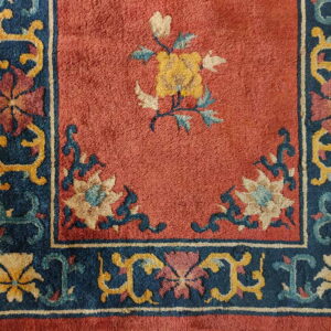 Red medium-pile rug featuring a navy floral border and a large central yellow and cream flower.