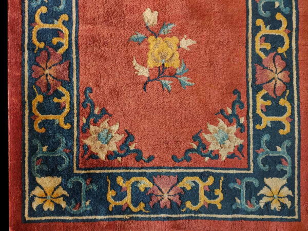 Red medium-pile rug featuring a navy floral border and a large central yellow and cream flower.