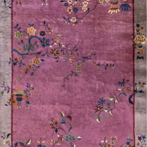 A magenta rug with a wide gray border features an ornate multi-colored pattern of sprawling flowers and vines.