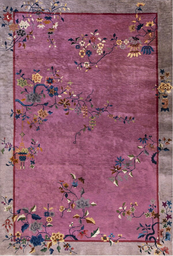 A magenta rug with a wide gray border features an ornate multi-colored pattern of sprawling flowers and vines.