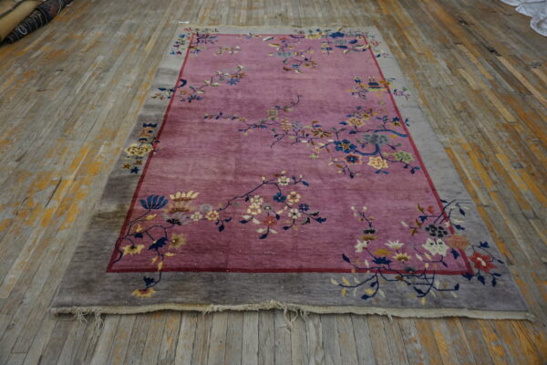 Mauve rug with colorful floral vines and a wide gray border on distressed wood plank flooring.