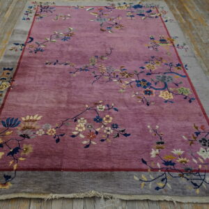 Low-pile purple rug features a floral pattern and wide taupe border displayed on rustic wood planks.