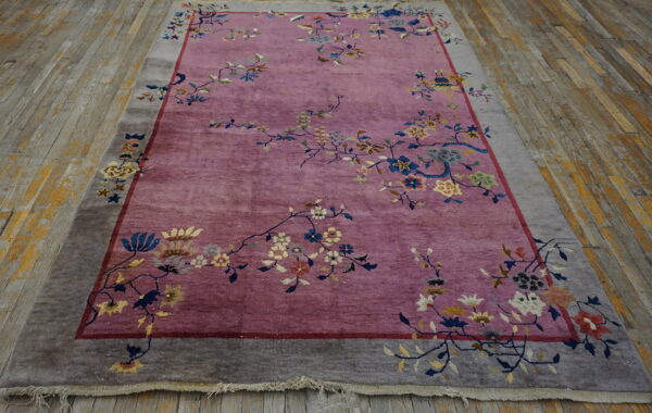 Low-pile purple rug features a floral pattern and wide taupe border displayed on rustic wood planks.