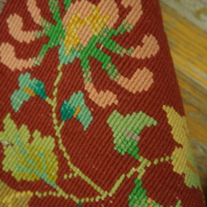 Woven textile detail features large pink and green geometric floral motifs on a deep red background.