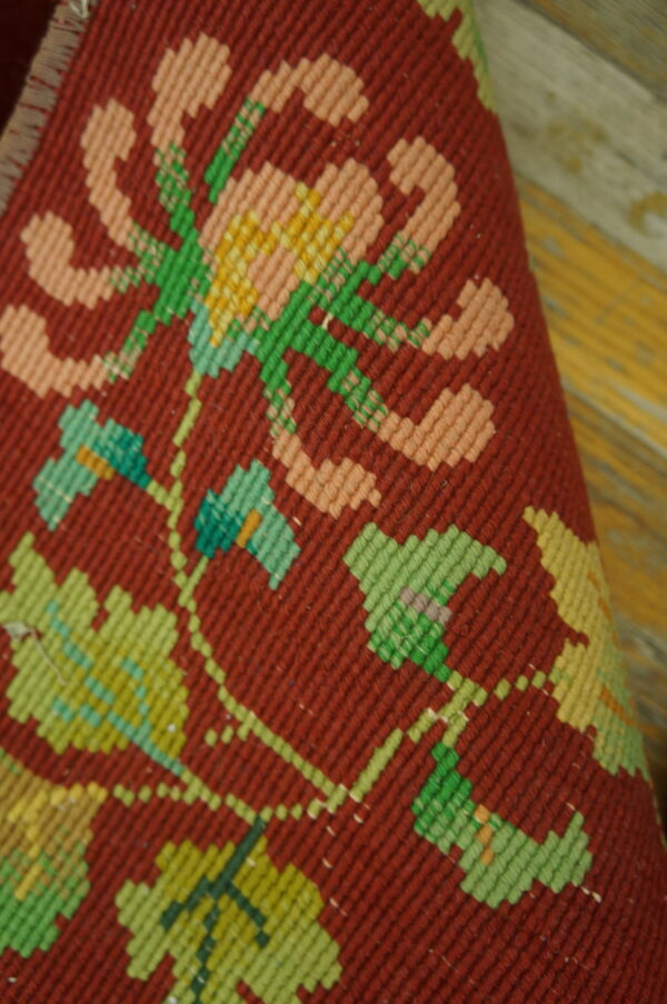 Woven textile detail features large pink and green geometric floral motifs on a deep red background.