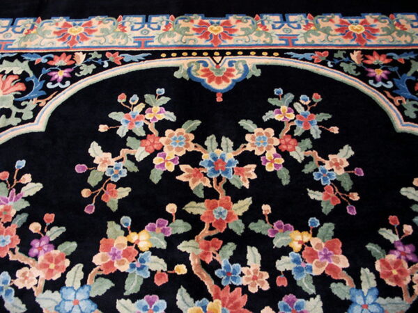 Black rug with multicolored floral design, a central arched field, and a detailed geometric border.