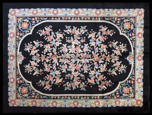 Black rug featuring a blossoming tree design in pink, blue, and green within an ornate central medallion.
