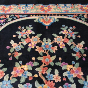 Plush navy rug detail showing colorful floral branches within an arched frame and geometric borders.