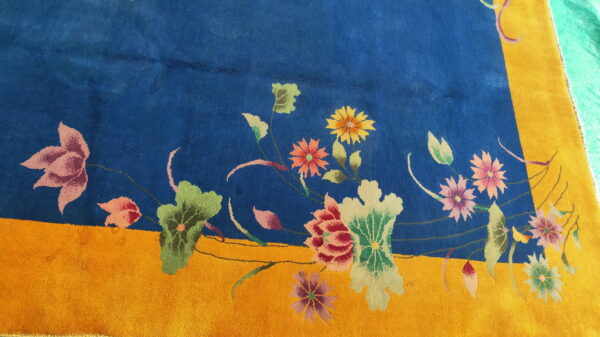 Colorful floral motifs decorate a deep blue rug field adjacent to a bright gold border.