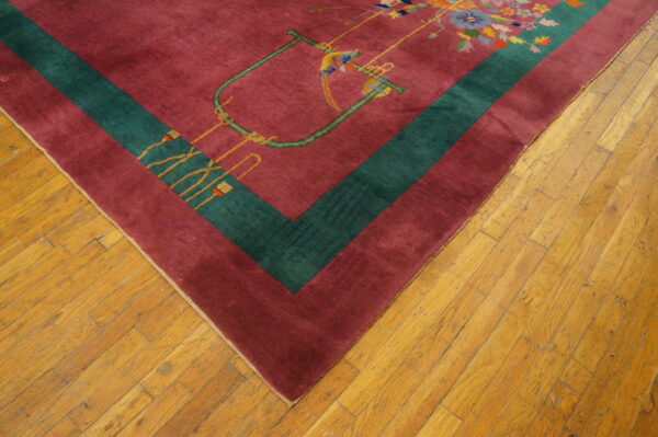 Magenta rug with a teal border and multi-colored floral and bird pattern on light brown hardwood flooring.