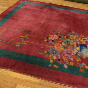 Magenta rug with a teal border and multi-colored floral and bird pattern on light brown wood floor