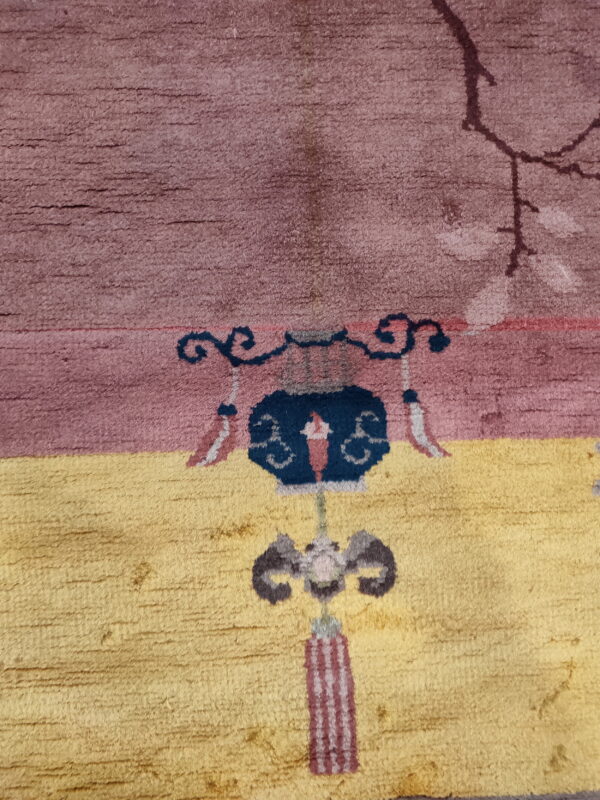 Textured pile rug featuring a dusty rose field above gold, centered with a navy blue and maroon motif.