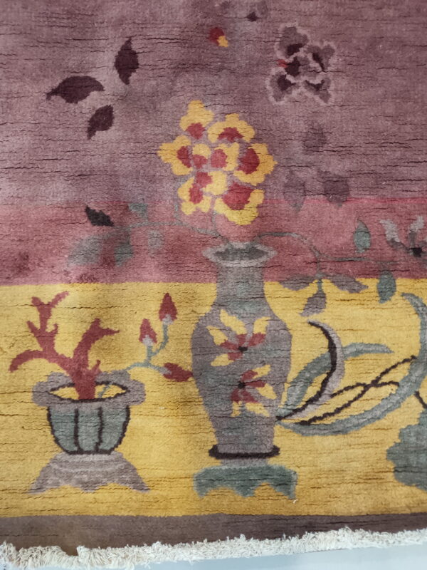 Pictorial rug detail featuring vases of yellow flowers and red coral on contrasting purple and gold fields.