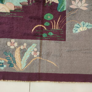 Cut-pile rug with a burgundy field, gray border, and stylized flowers on light tile flooring.