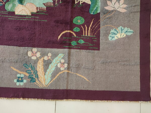 Cut-pile rug with a burgundy field, gray border, and stylized flowers on light tile flooring.