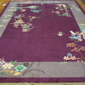 Plum-colored rug with gray borders featuring scattered flowering branches and birds on a wood floor.
