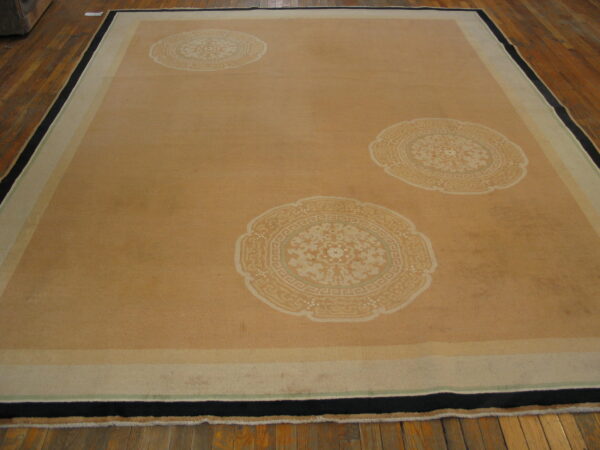 Tan rug with three large cream medallions featuring floral and geometric patterns, framed by a striped border.