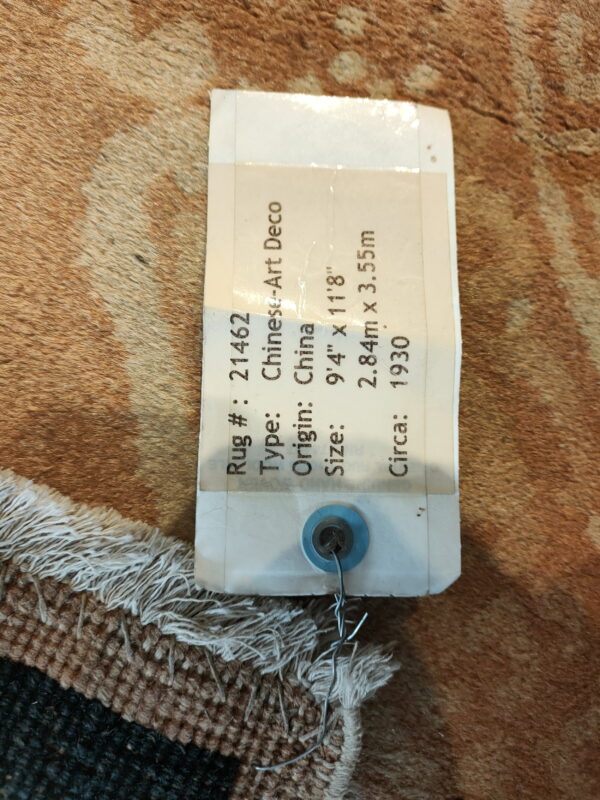 Detailed view of a sales tag secured to a high-pile rug showing brown and tan colors and white fringe.