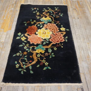 Black runner rug featuring yellow, coral, and teal floral branches laid on distressed wooden flooring.