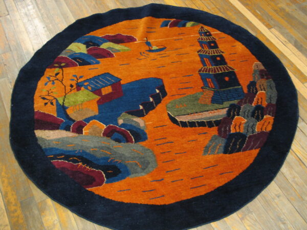 Round rug with a navy blue border and an orange field displaying a colorful scenic design on wood floors.