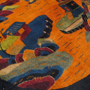 High-pile circular rug featuring an abstract orange field with large blue, green, and maroon stylized designs.