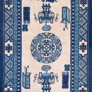 A rectangular runner rug in navy and light blue patterns against a light beige field on hardwood flooring.