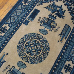Beige rug with dark and medium blue traditional geometric patterns and symbolic motifs on a wooden floor.