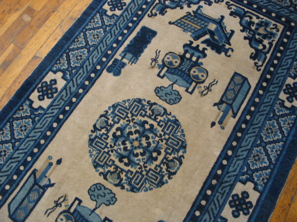 Beige rug with dark and medium blue traditional geometric patterns and symbolic motifs on a wooden floor.
