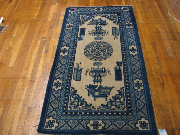 A navy blue and tan runner rug featuring stylized vases and geometric borders on warm wood flooring.