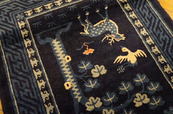 Dark blue high-pile rug with a detailed geometric border and central animal motifs in pale yellow and light blue.