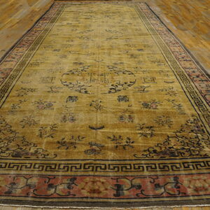 Gold runner rug featuring dark floral motifs and rust borders on warm parquet wood floors.