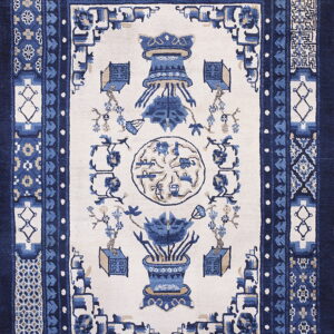 Traditional blue and cream rug with multiple intricate borders and stylized central floral and vessel motifs.