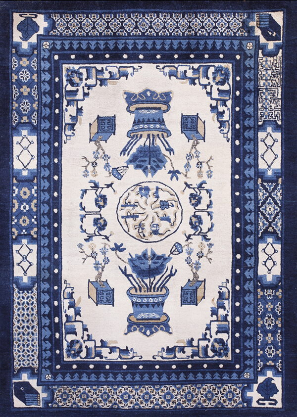 Traditional blue and cream rug with multiple intricate borders and stylized central floral and vessel motifs.
