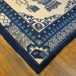 Blue and cream traditional rug corner with ornate borders resting on glossy wood planks.