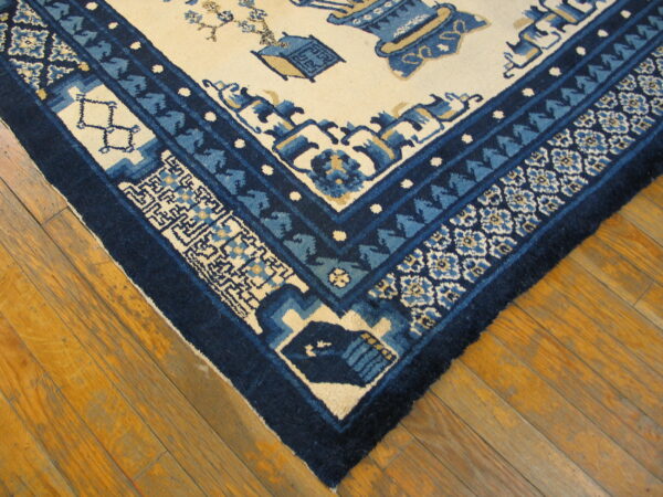 Blue and cream traditional rug corner with ornate borders resting on glossy wood planks.