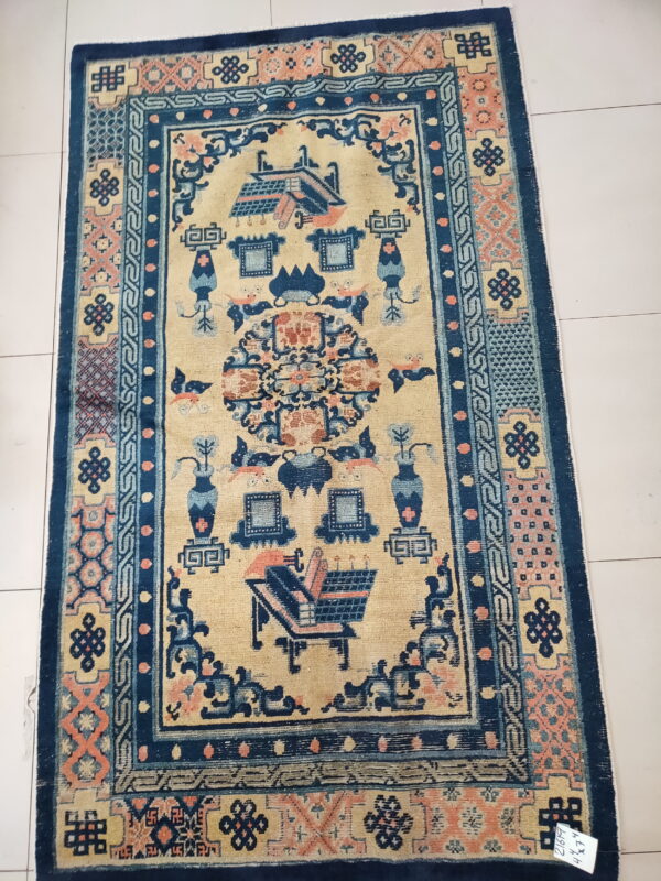 Cream rug with complex blue and peach figures and geometric borders on a light tiled floor.