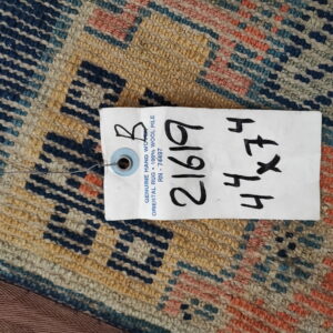 Navy, tan, and coral low-pile rug with a geometric pattern, partially obscured by a large product tag.