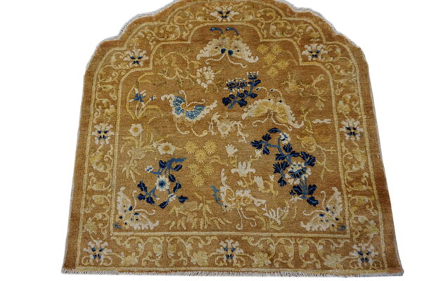Arched brown rug with navy blue and cream floral motifs, surrounded by complex tan borders.