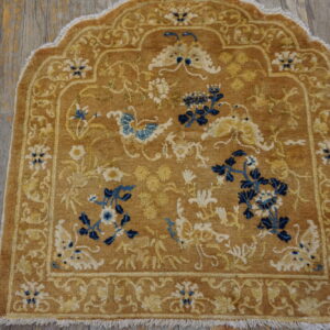 Camel-colored, arched rug featuring blue and cream floral motifs on distressed wood floors.