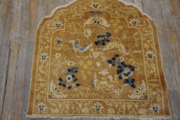 Camel-colored, arched rug featuring blue and cream floral motifs on distressed wood floors.