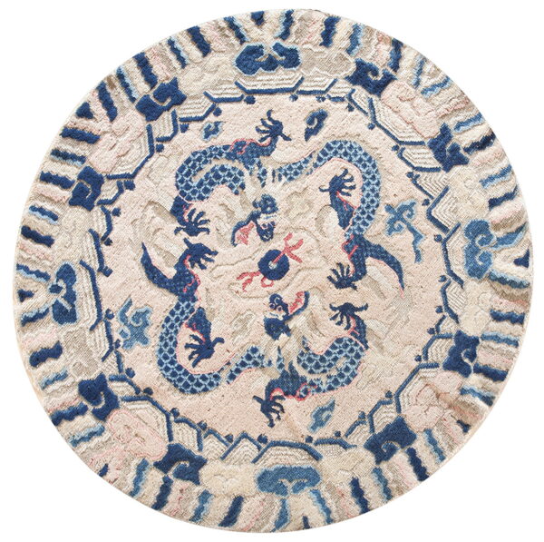 Round rug with a carved blue dragon design on a textured pale pink and beige background.