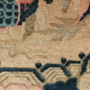 Detailed texture of a rug featuring high pile in tan and peach with contrasting dark teal patterns.