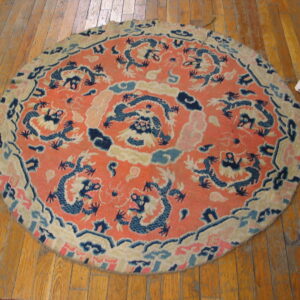 Round orange and blue dragon-patterned rug rests on distressed wood flooring.