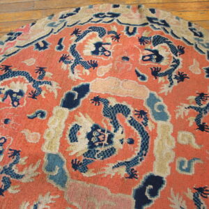 Semicircular coral rug with dark blue and cream stylized patterns sits on wood plank flooring.
