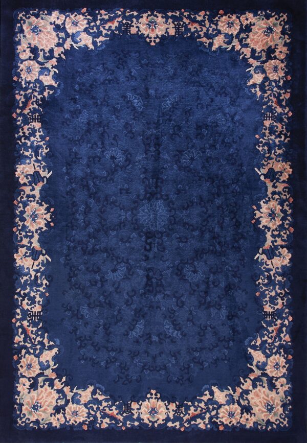 Deep navy blue rug with a carved floral field and a wide border of blush pink and dark blue blooms.