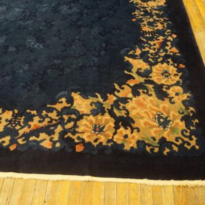 High-pile navy rug with carved gold and rust floral border resting on yellow wood planks.