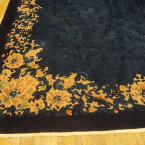 A dark blue rug with an ochre and orange floral border rests on a yellow-toned glossy hardwood floor.