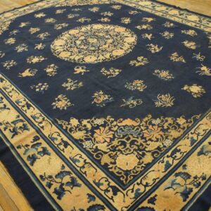 Large square rug in dark blue with intricate central medallion and beige borders on wooden floors.