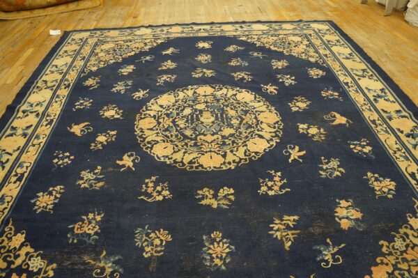 Wool hand knotted pile blue antique rectangle 1890s rug 4 Large low-pile dark blue rug with intricate pale yellow and blue patterns displayed on wooden flooring.